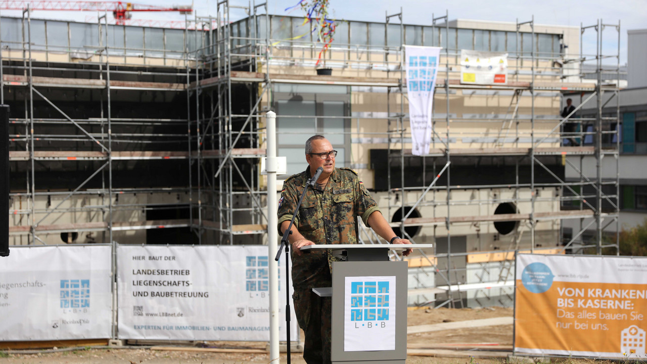 Generalarzt Dr. Jens Diehm, Kommandeur und Ärztlicher Direktor des Bundeswehr-Zentralkrankenhauses steht an einem Rednerpult. Im Hintergrund sieht man den fertiggestellten Rohbau des Interimsgebäudes für die Intensivstation der Inneren Medizin.